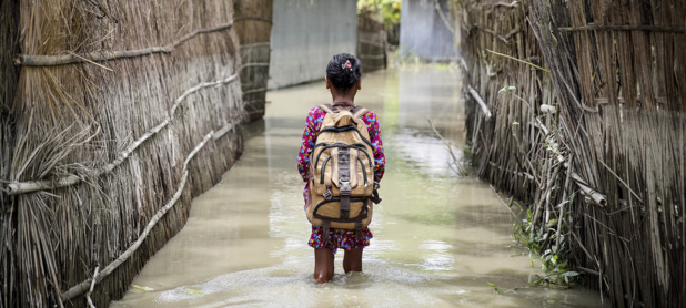 UNICEF/Akash Un enfant patauge dans les eaux en se rendant à l'école dans le district de Kurigram, dans le nord du Bangladesh, lors des inondations d'août 2016.