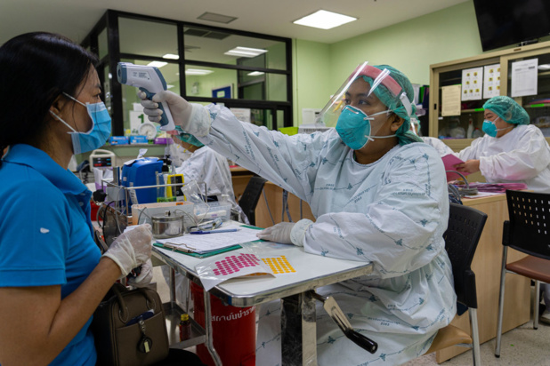 ONU Femmes/Pathumporn Thongking Un agent de santé vérifie la température d'une patiente dans un hôpital de la province de Nonthaburi, en Thaïlande.