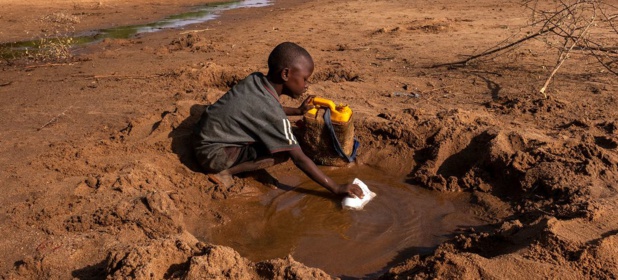 © UNICEF/Sebastian Rich  Un garçon collecte le peu d'eau qu'il trouve dans une rivière asséchée en raison de la sécheresse à Dollow, en Somalie